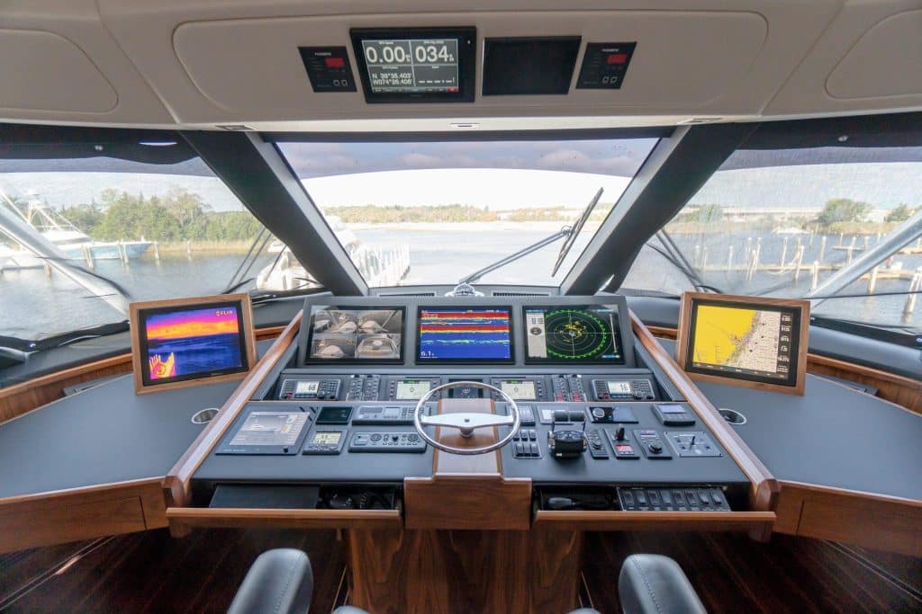 Boat helm with multiple displays and a steering wheel in a wood-trimmed console