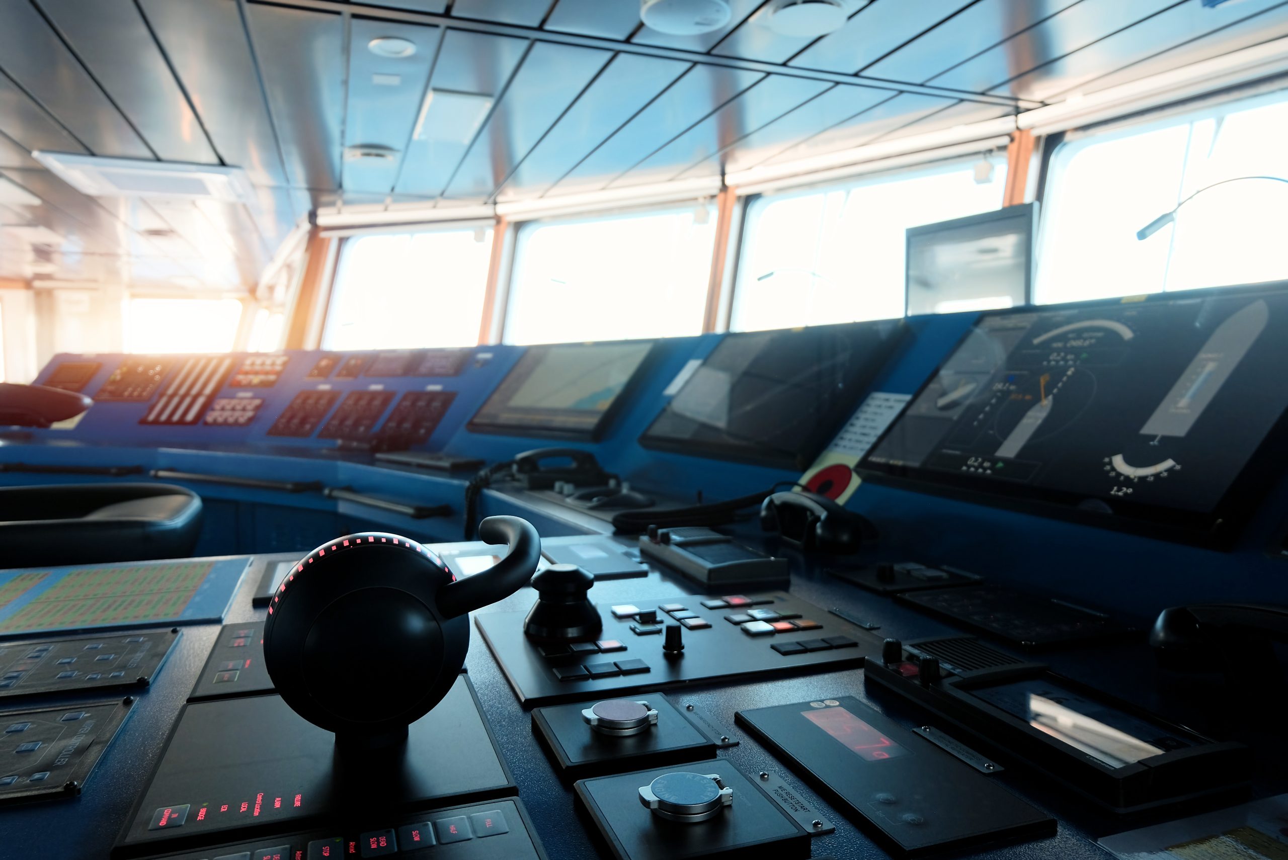 Modern ship bridge wheelhouse control console with multiple navigation displays, helm wheel, and chart-display monitors - real photograph illustrating a marine touchscreen helm environment.