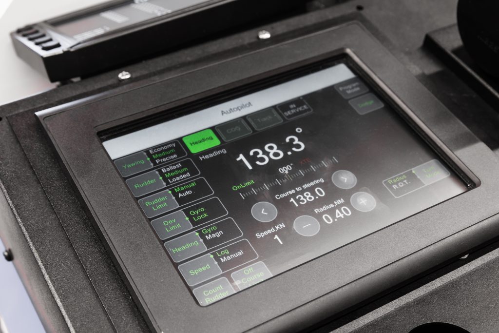 Closeup of a marine touchscreen digitizer surface on a ship bridge navigation console, illustrating the procurement decision moment for a marine-grade sensor stack.