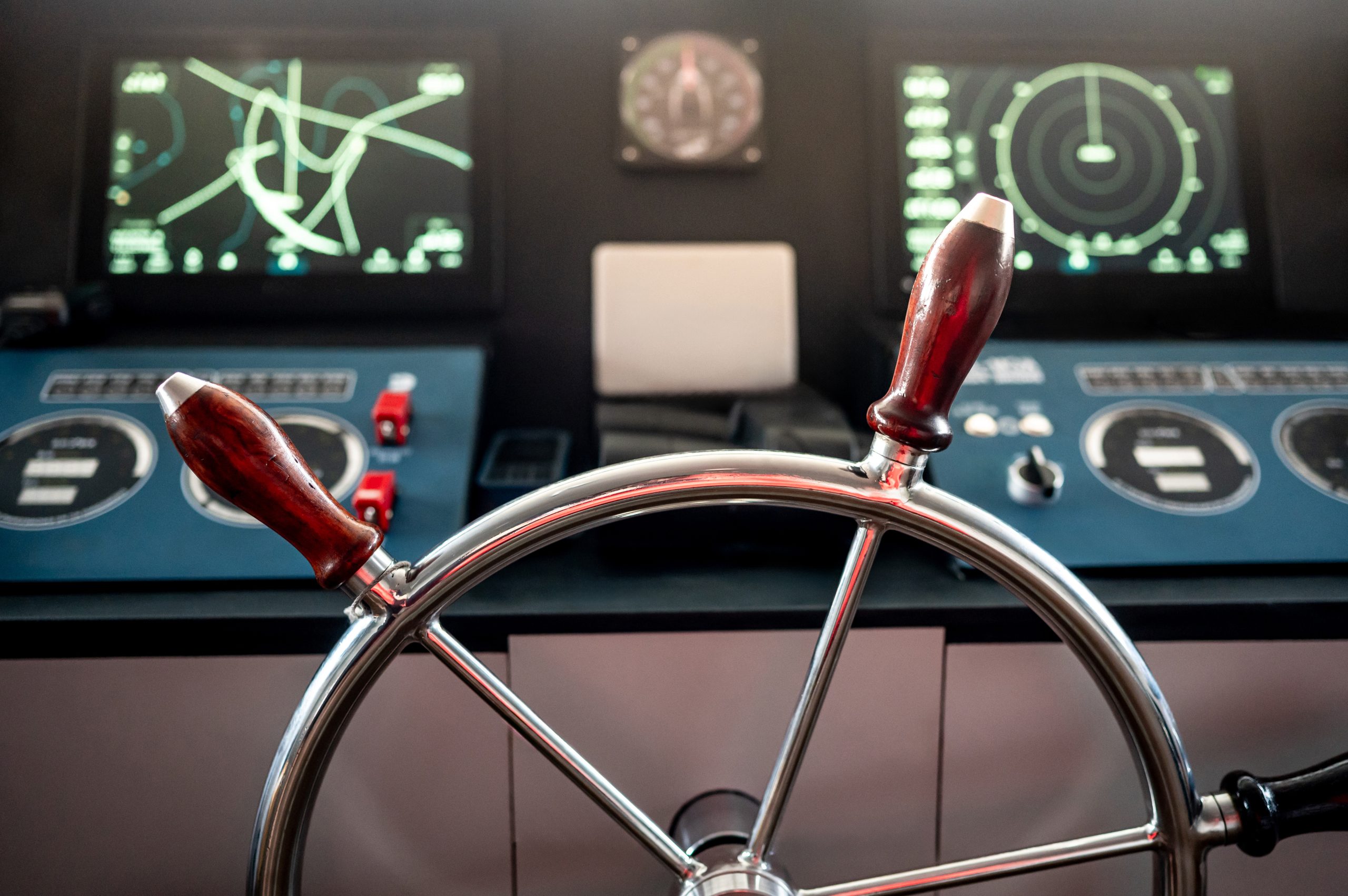 A magnetic steering compass in its binnacle beside a marine navigation display on a ship's bridge, representing the compass safe distance decision when mounting a helm screen.