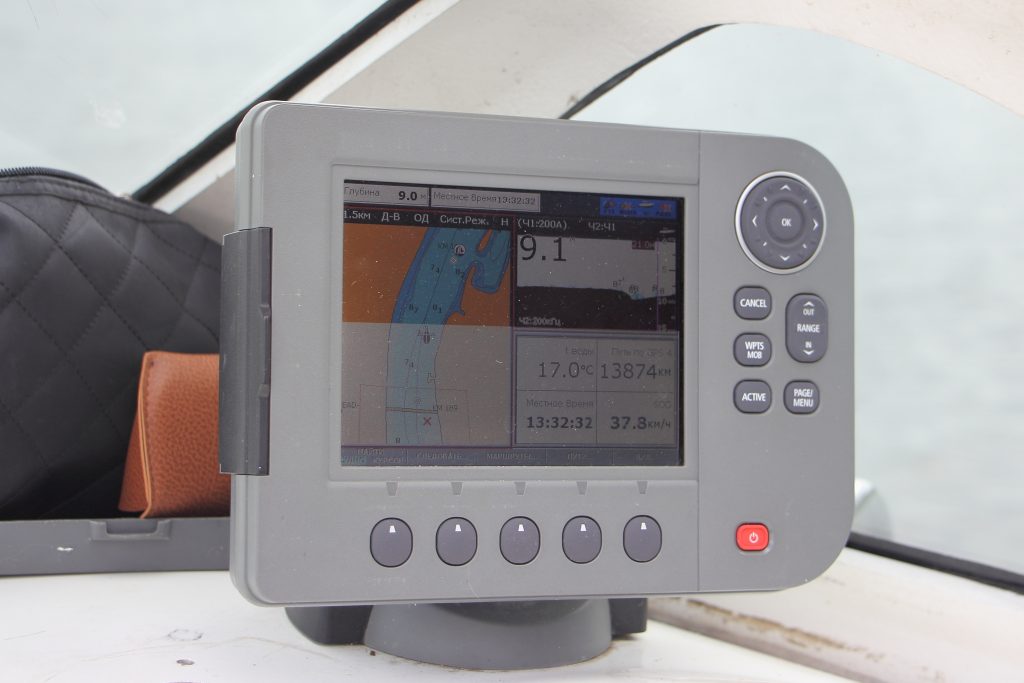 A modern multifunction marine display mounted on a motorboat helm dashboard showing a live navigation and depth screen, representing the helm display that has to render a sonar feed.